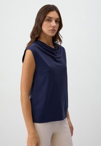 Top senza maniche di un blu navy, con un design a scollo drappeggiato, realizzato in un tessuto morbido, caratterizzato da una vestibilità comoda e una texture liscia.