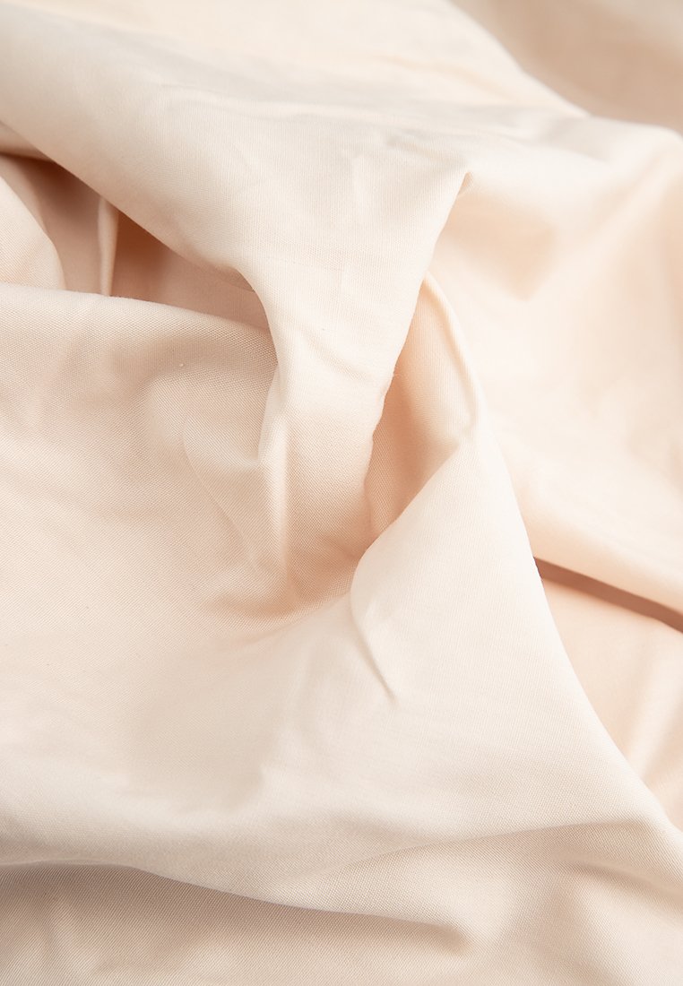 Tissu beige clair avec une texture lisse, légèrement froissé, présentant une apparence douce et légère. Aucun motif ou accent visible.