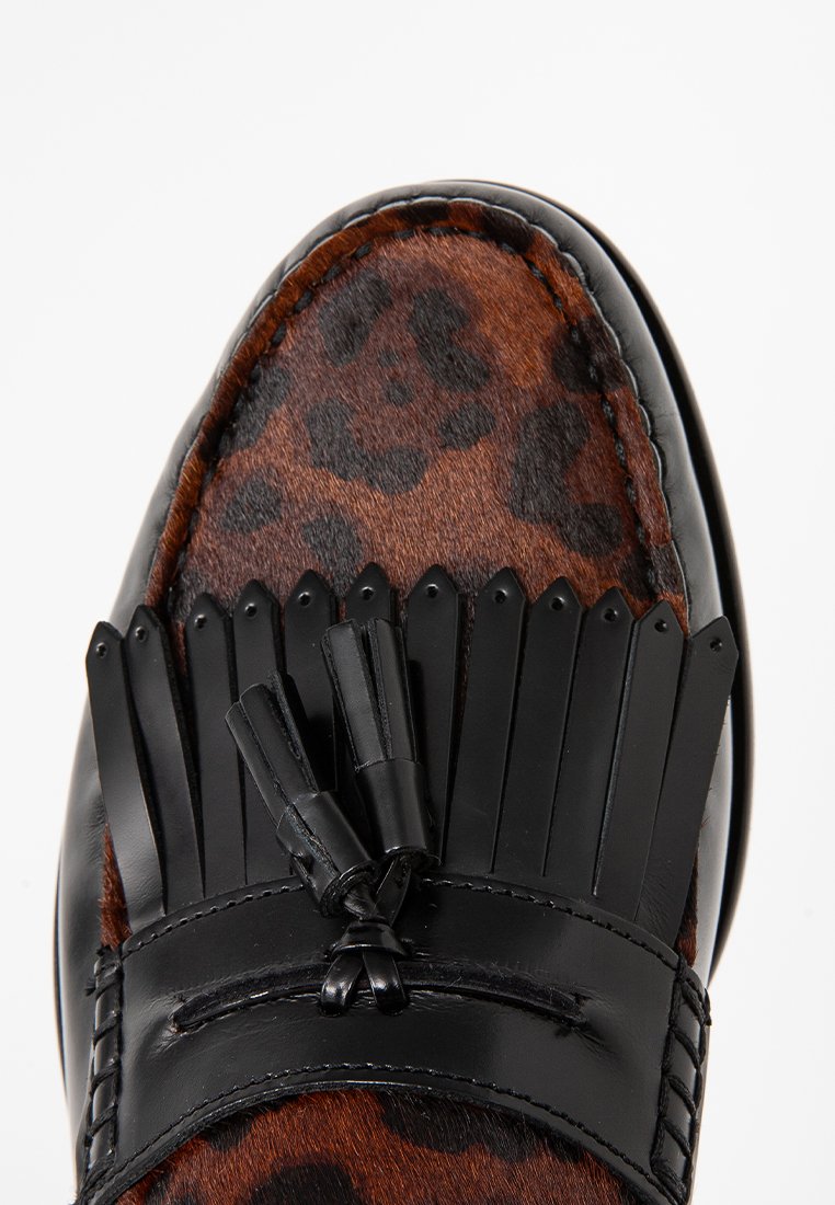 Mocassino in pelle con stampa leopardata e dettagli in pelle nera, con orlo frangiato e nappe decorative sul davanti.