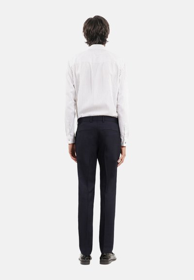 Wit gestreepte overhemden met knoopsluiting, gecombineerd met marineblauwe broek. Het shirt heeft een klassieke kraag en lange mouwen, met subtiele textuur en stiksels.
