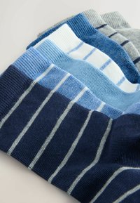 Różnorodne skarpetki z paskami w różnych odcieniach niebieskiego, granatu, bieli i szarości, o gładkiej dzianinowej fakturze i ściągaczowych mankietach.