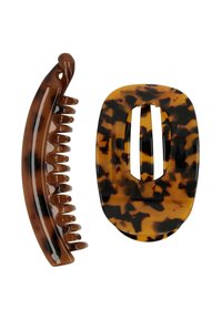 Due accessori per capelli: una clip tartaruga con superficie liscia e una clip a pinza marrone ondulata con denti arrotondati e finitura lucida.
