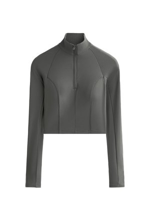 Grijze, langarmige cropped top met hoge kraag en kwart ritssluiting. Heeft een geribde textuur en gecontourde panelen op de schouders en zijkanten.