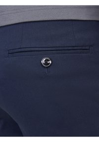 Marinblå byxor med en bakficka som har en enkel knappstängning och en slät, strukturerad tygkvalitet. Enkel och funktionell design.