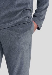 Pantalones de chándal de algodón gris con una textura suave, que cuentan con un bolsillo lateral y una cinturilla elástica para mayor comodidad.