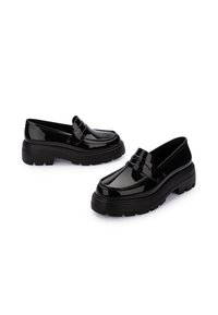 Mocasines de charol negro con suelas gruesas de goma negra texturizada. Diseño clásico con un sutil detalle de costura y una correa frontal elevada.