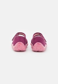 Lila tygskor med rosa gummisulor, med en strukturerad design och justerbara remmar på baksidan för enkel påtagning.