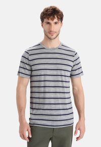 Szara koszulka w paski z bawełnianego materiału; posiada pionowe granatowe paski, okrągły dekolt, krótkie rękawy oraz luźny krój.