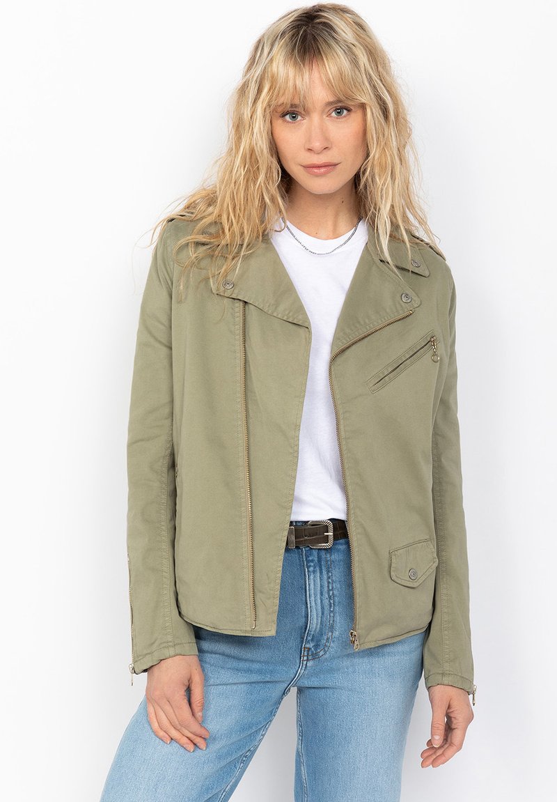 Giacca verde oliva con chiusura a zip, tasca inclinata sul petto e spalline. Il tessuto sembra liscio; presenta un design strutturato e corto.