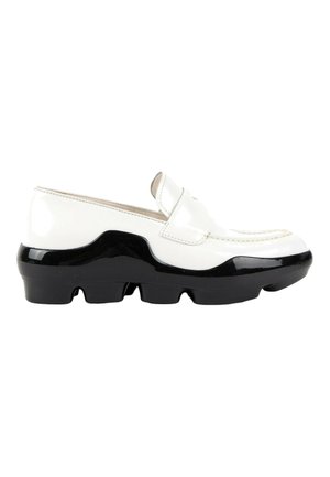 White leather loafer with high-gloss black chunky sole featuring deep grooves, and a classic penny strap design on the top.