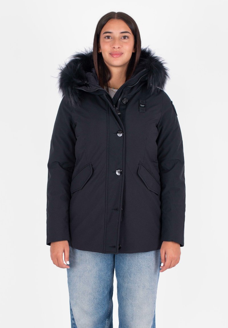 Chaqueta negra aislante con capucha con borde de piel, cierre de botones y dos bolsillos laterales. La tela parece suave y duradera.