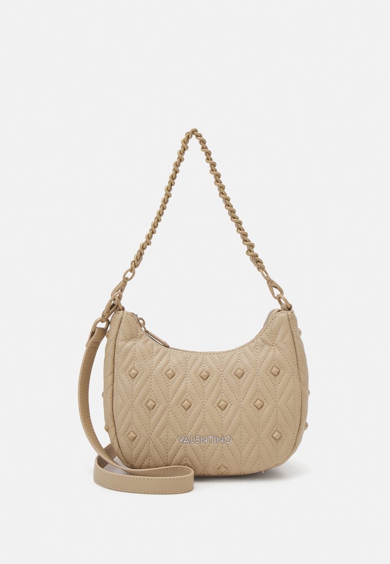 Quilted beige leather shoulder bag with a chain strap, featuring diamond patterns, branded logo, and curved silhouette. Zipper closure.