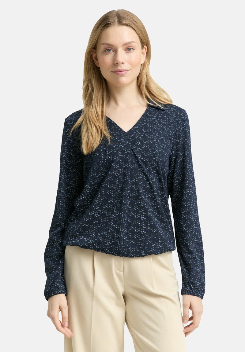 Marineblaue langärmlige Bluse mit V-Ausschnitt, verziert mit einem strukturierten Muster in Hellblau. Lockerer Schnitt mit gerafftem Detail an der Vorderseite.