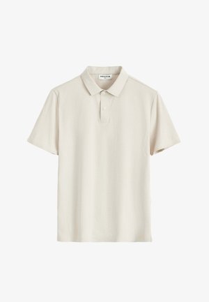 Polo à manches courtes beige clair avec col et patte à deux boutons, présenté à plat avec une étiquette de marque visible à l'intérieur du col.