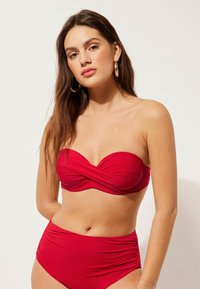 Červený bikiny set s twistovaným bandeau topem a vysokými kalhotkami, vyrobený z hladkého, elastického materiálu s přiléhavým střihem.