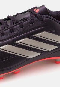 Black soccer cleat with silver three-stripe design, red accents, textured upper, and orange sole. Laces run through a reinforced eyelet.