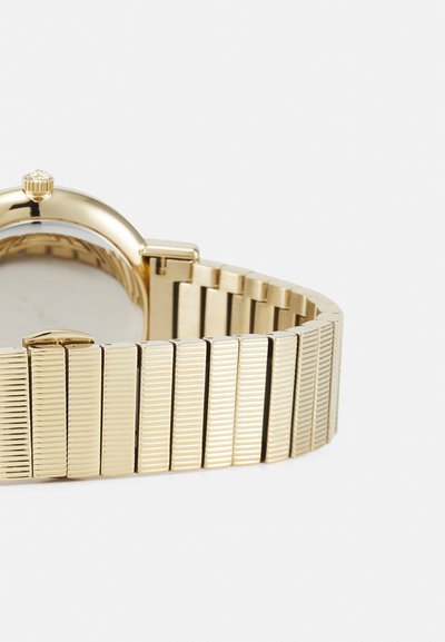 Kuldvärvi kell, millel on tekstuuriga metallkäevõru, elegantse ümmarguse korpuse ja 12. tunni asukohas asuva krooniga.