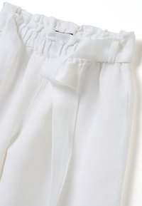 Witte linnen broek met een verzamelde elastieken tailleband, voorzien van een stoffen strik en een gladde textuur. Gestructureerde plooien voegen dimensie toe.