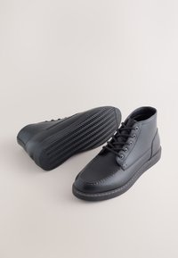 Schwarze Leder-Stiefeletten mit glatter Textur, runder Zehenpartie und kontrastierenden Nähten. Verfügen über eine Gummisohle mit Fischgrätmuster.