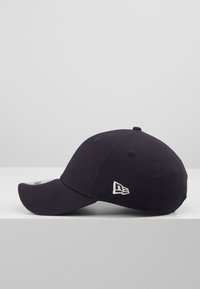 Fekete baseball sapka ívelt karimával, pamut anyagból készült. Az oldalán hímzett fehér logó található, valamint varrott szellőző lyukak.