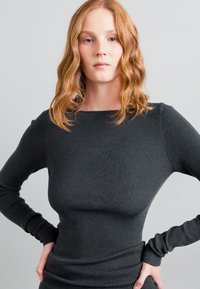 Black ribbed long-sleeve top with a form-fitting design and a rounded neckline. The fabric has a smooth texture and stretches for comfort.