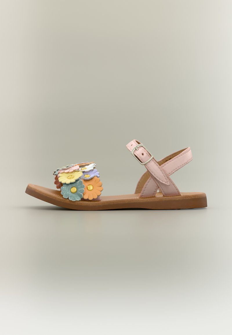 Sandale plate avec des lanières roses et des décorations florales multicolores sur la lanière avant, avec une boucle argentée sur la lanière de la cheville.