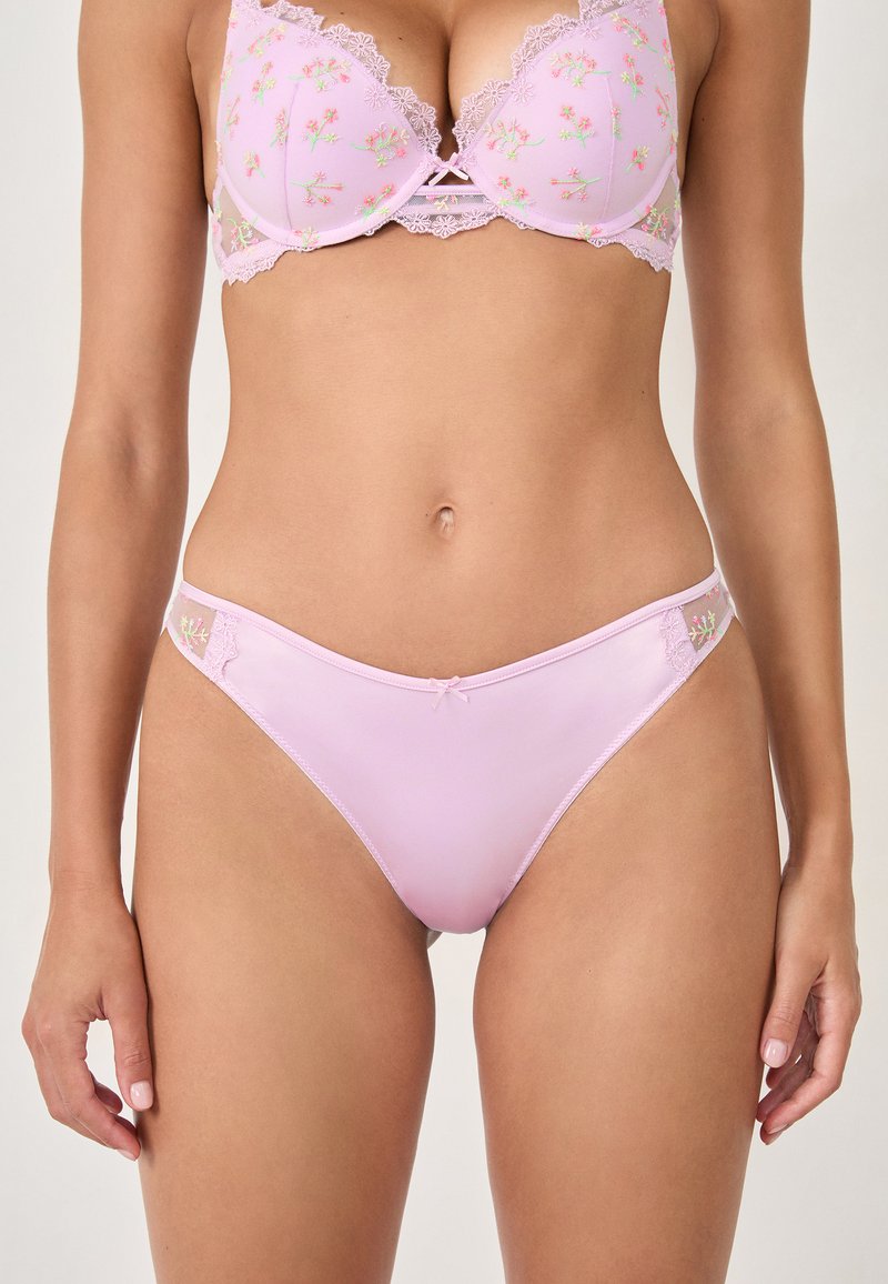 Set di lingerie rosa chiaro con ricami floreali, composto da un reggiseno imbottito con bordi in pizzo e coordinato da delle mutandine in stile bikini con accentuazioni laterali.