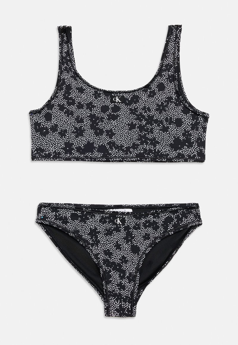 Bikini deux pièces noir et blanc tacheté avec un haut à encolure dégagée et un bas de bikini taille moyenne, tous deux ornés d'un petit logo CK à l'avant.