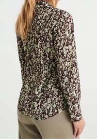 Långärmad blus i mörkbrunt, med ett grönt och vitt blommönster. Slät tyg med krage och knappade manschetter.