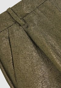 Zeleni metalik materijal s teksturiranim završetkom, s nabranim dizajnom i pojasom za strukturirani izgled.