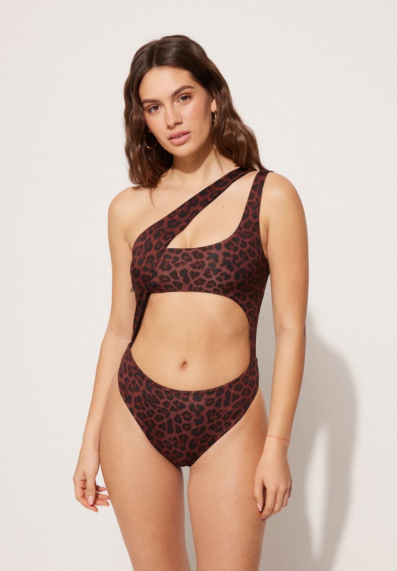 Hnědý plavky s leopardím vzorem v jednom kuse, které mají asymetrický design, výřezové strany a jedno ramínko. Hladká textura látky.