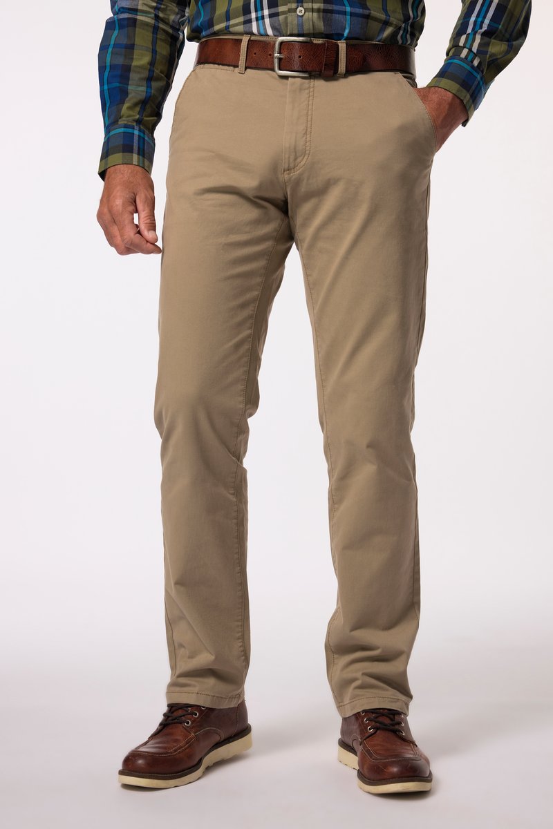 Man draagt beige chino's, een bruine leren riem, bruine leren schoenen en een blauw-groen-wit geruit overhemd, staand met één hand in de zak.