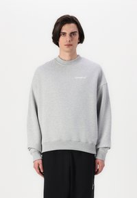 Gray sweatshirt in soft fabric with a crew neck, relaxed fit, and ribbed cuffs. Features a white logo on the left chest. Minimalist design.