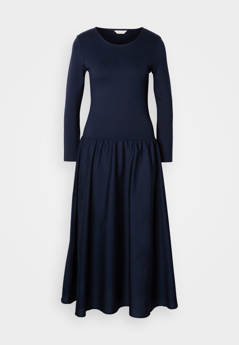 Robe bleu marine à manches longues avec un col rond et une taille froncée, présentant une jupe fluide et une texture de tissu douce.