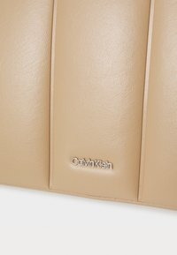 Bežna kožna torba s kviltanim dizajnom, srebrnim logotipom Calvin Klein i glatkom teksturom. Kompaktni oblik s horizontalnim šavovima.