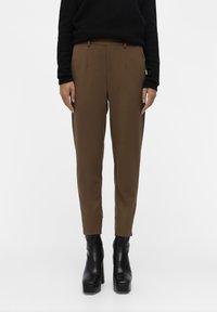 Brune skreddersydde bukser med en jevn tekstur, med frontlommer og en smalere design. Kombinert med svarte platåsko.