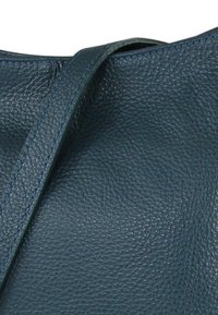 Leren handtas met een getextureerd donkerblauw oppervlak en contrasterende blauwe stiksels. Voorzien van een enkele schouderriem en een zachte structuur.