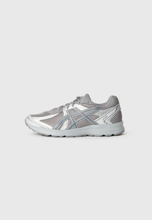 Gray athletic shoe with a breathable mesh upper and silver accents. Features a padded collar, lace-up design, and a textured rubber sole.