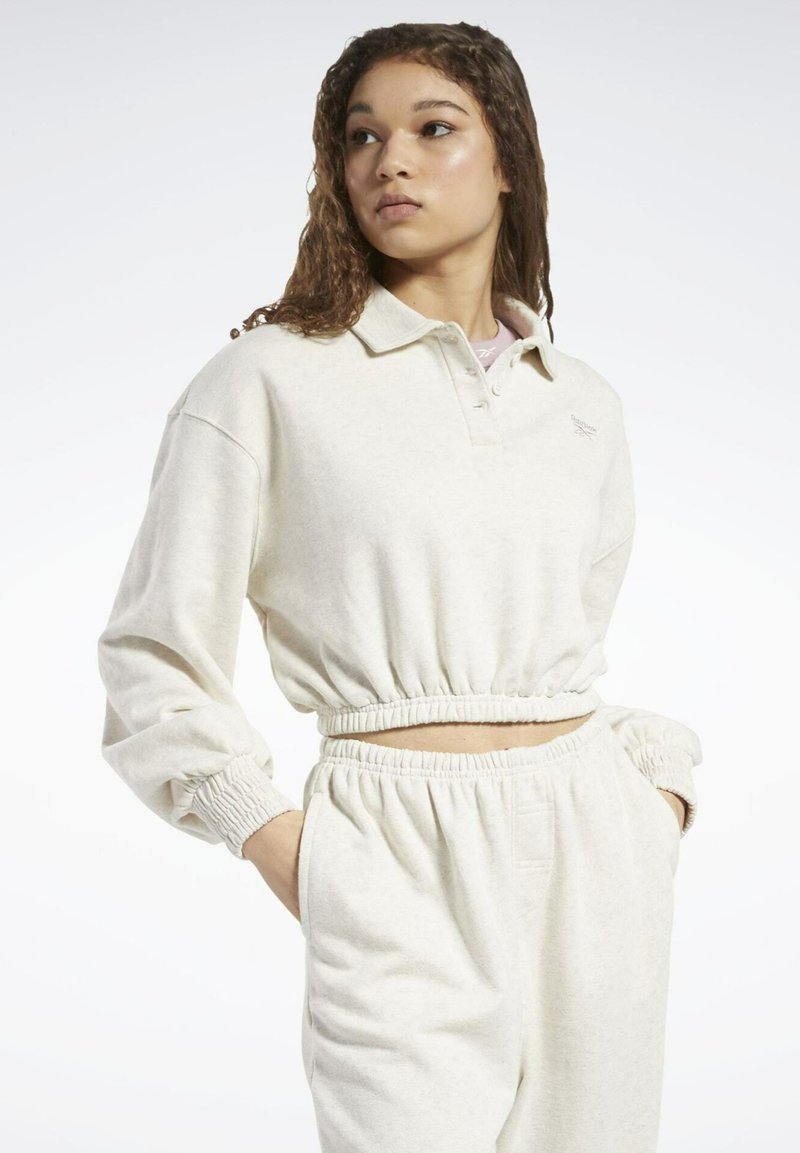 Cremefarbener Pullover mit Kragen, elastischem Bund und Bündchen. Kombiniert mit passenden, lässigen Hosen mit elastischem Taillenbund.