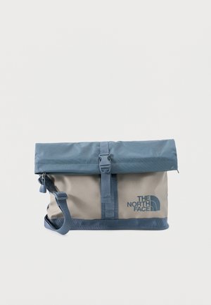 Bolso de hombro North Face de dos tonos gris y azul con cierre de solapa enrollable, correa ajustable y hebilla frontal.