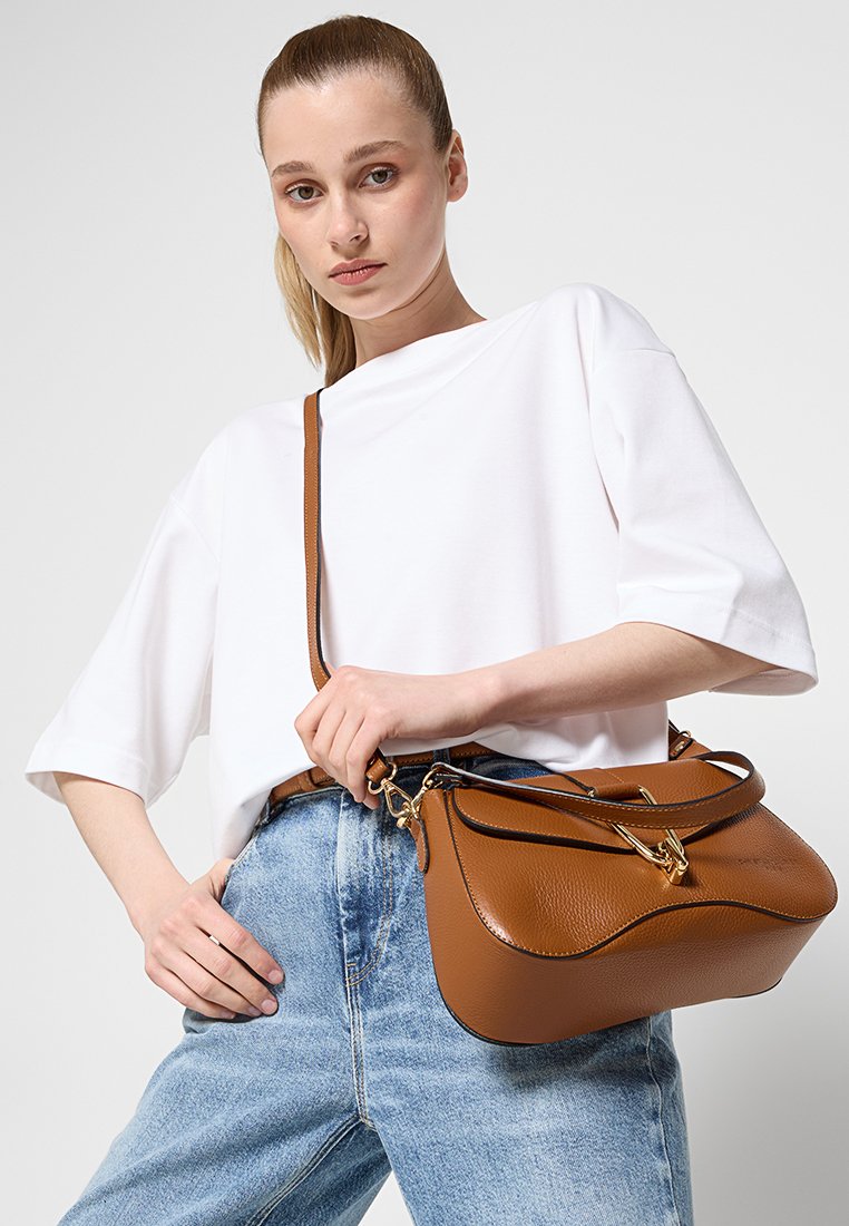 Sac à main en cuir marron avec une surface texturée, un design courbé, une poignée supérieure et une longue sangle, avec des détails en métal doré.
