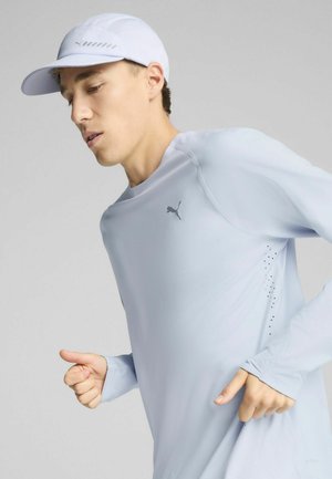 Lichtblauw sportshirt met lange mouwen en een snug fit, met een subtiele PUMA-logo en geperforeerde details aan de zijkant. Witte pet met mesh panelen.