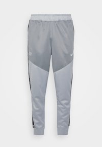 Grå träningsbyxor med elastisk midja, avsmalnande ben och sidopaneler i en mörkare grå, med Nike-logotypen i vitt.