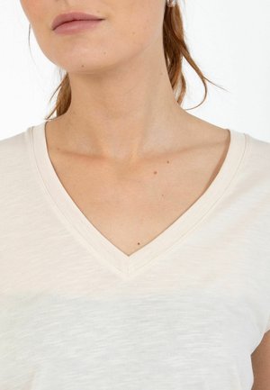 Roomkleurig V-hals T-shirt gemaakt van zacht materiaal, met een lichte gemêleerde textuur en een losse pasvorm, voorzien van zichtbare stiksels rondom de halslijn.