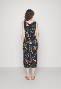 Maxikleid mit floralen Mustern auf schwarzem Hintergrund, das große grüne und pinke tropische Drucke zeigt, mit V-Ausschnitt und gerafftem Taillendetail.