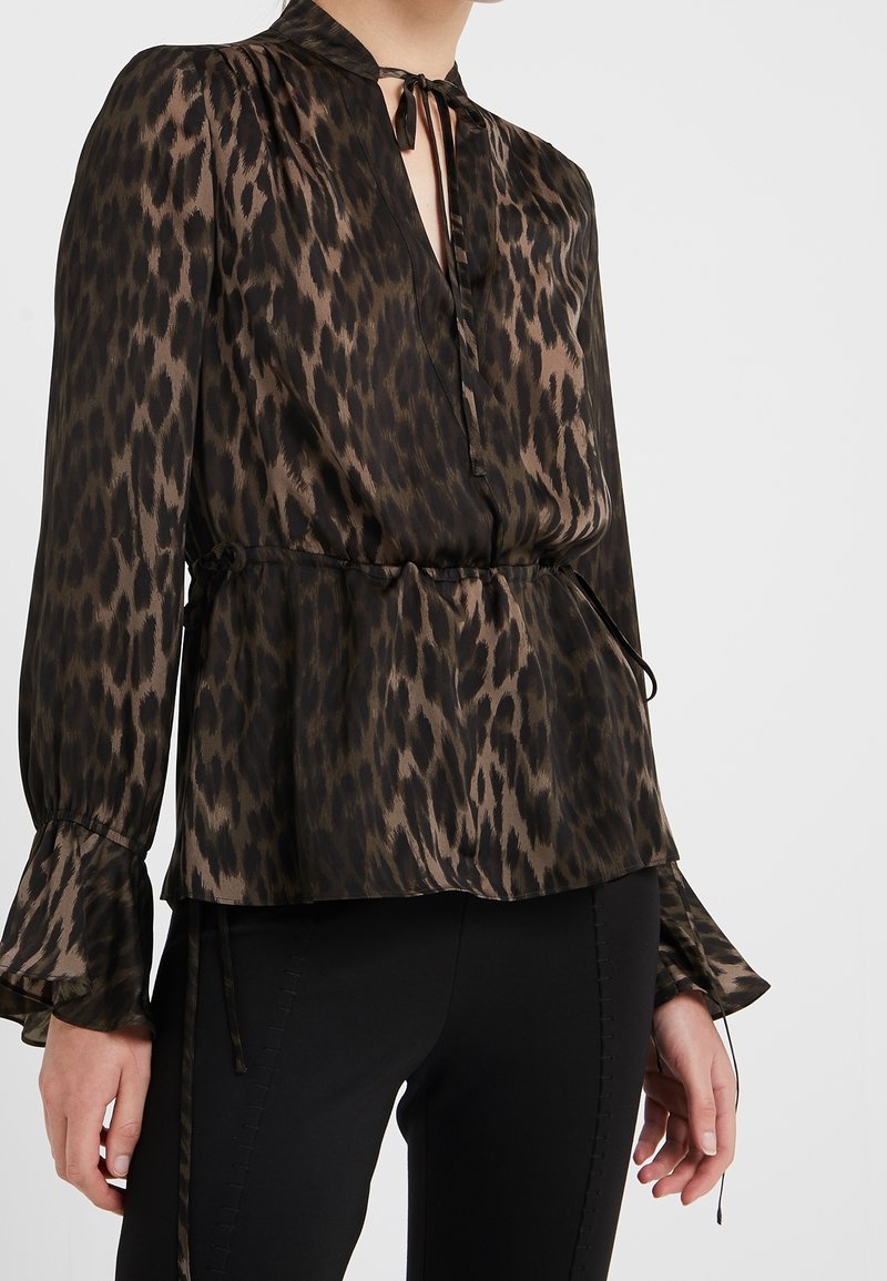 Blusa con stampa leopardata in marrone scuro e nero, dotata di collo a cravatta, maniche lunghe con polsini svasati e vita regolabile con cordoncino.