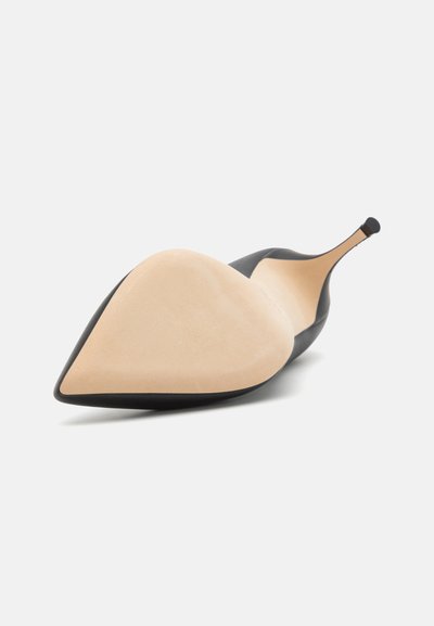 Pump noir à bout pointu avec une tige lisse et mate, semelle en daim beige et talon fin. Présente un design élégant avec une silhouette minimaliste.