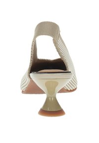Zapato de slingback de tela beige con tacón blanco curvado, presenta una textura estriada horizontal y punta redondeada. El interior cuenta con un acolchado minimalista.