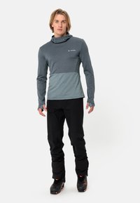 Langarm-Pullover in Dunkelgrau mit hellgrauem Brustpanels. Mit Kapuze, Daumenlöchern und schwarzen technischen Hosen mit verstellbaren Bündchen.