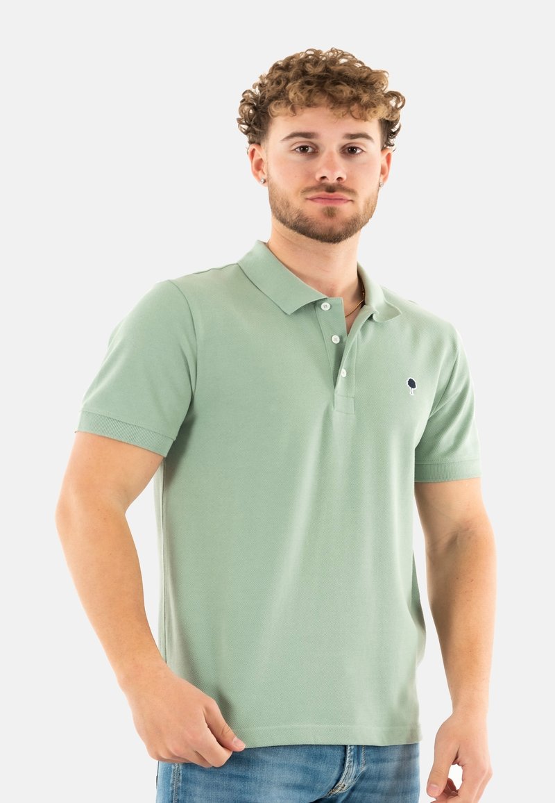 Polo de manga corta verde claro hecho de algodón. Presenta una tapeta de tres botones y un pequeño logotipo en el lado izquierdo del pecho. Textura lisa.